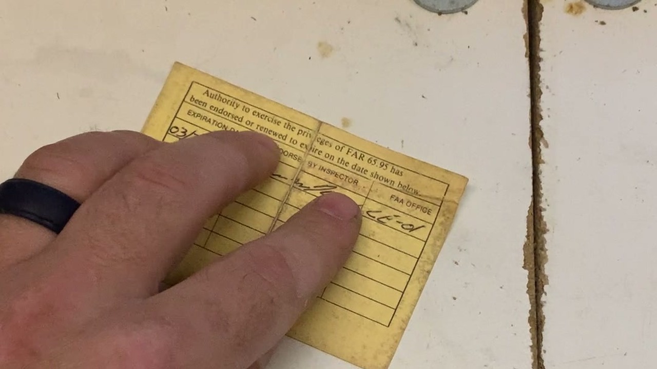 FAA Inspection Authorization (IA) card on a mechanic's workbench, showing the renewal endorsement grid