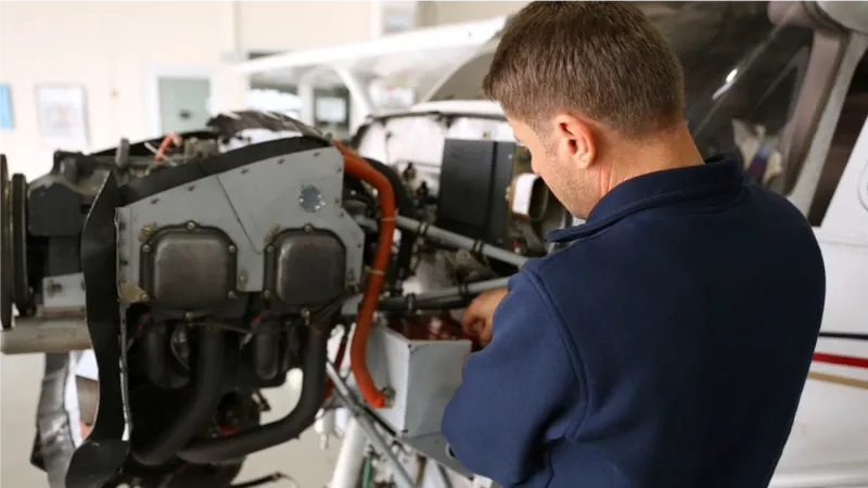 An aircraft mechanic working on a piston engine